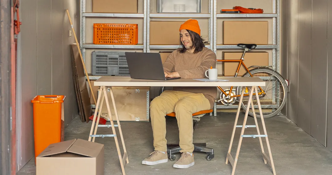 Man sitter i ett garage och jobbar på sin bärbara dator