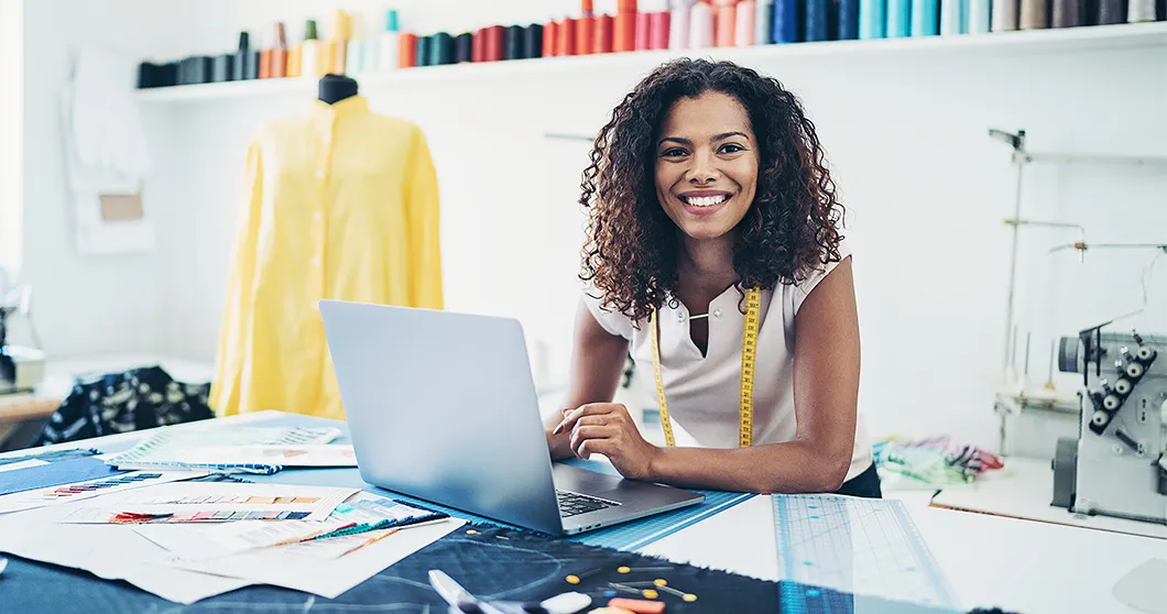 Modedesigner i studio med bärbar dator