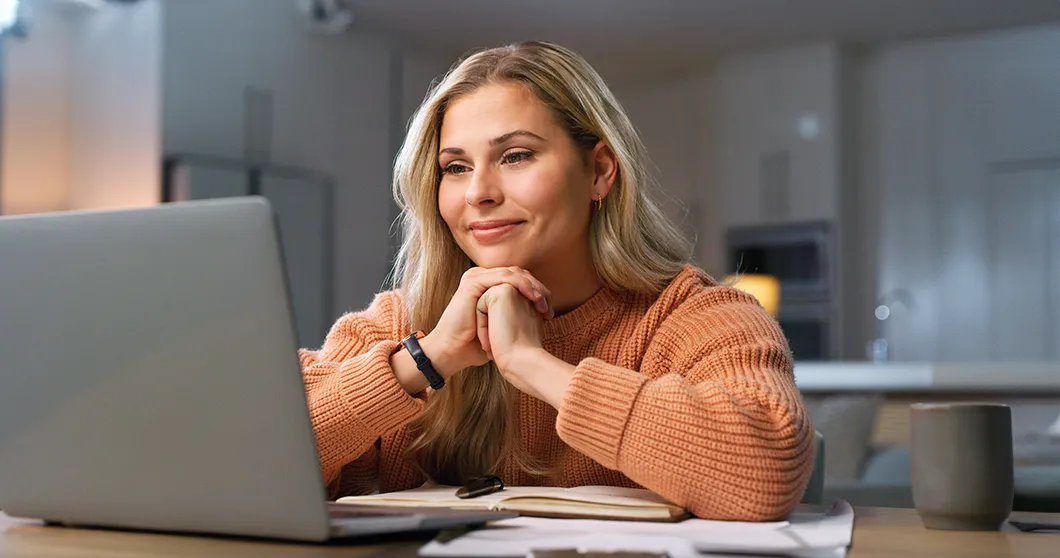Glad kvinna hemma på sin laptop